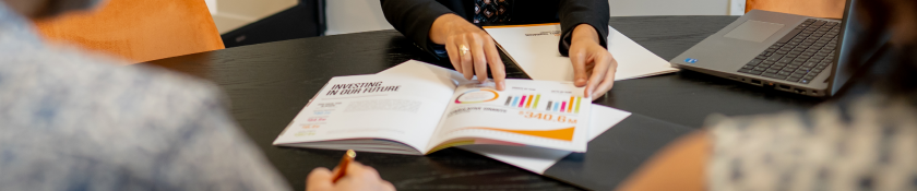hand pointing at colorful graphs on top of a table