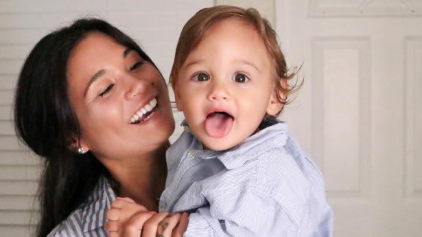 Mother holds toddler son as they smile together.